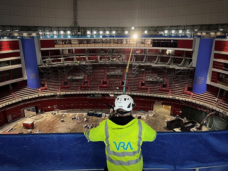 Medarbetare i varselväst med VRA:s logotyp blickar ut över Avicii Arena under ombyggnad