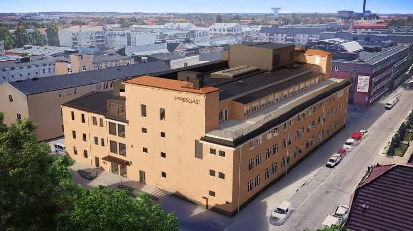 Vega i Uppsala, en gulbeige flervåningsbyggnad mitt i stadsbebyggelsen, sedd snett uppifrån